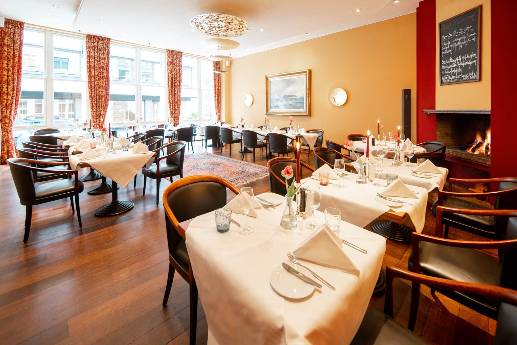 Blick in das Kaminzimmer im Restaurant mit eingedeckten Tischen